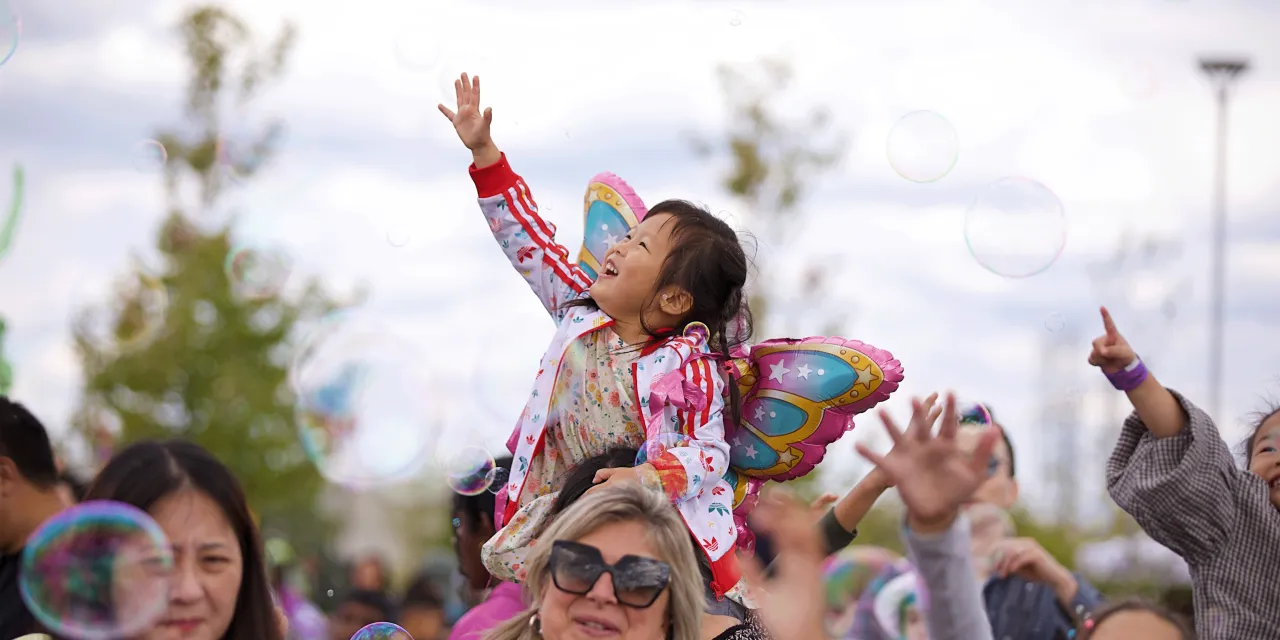 Child playing with bubbles at event.