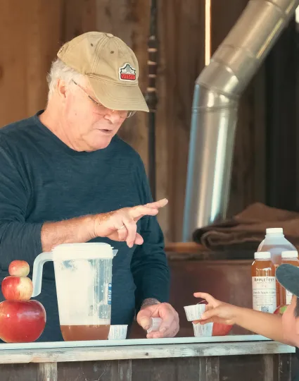 Person serving apple cider to child.