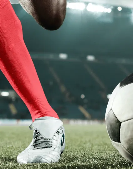 Soccer player in a stadium winding up to kick the ball.