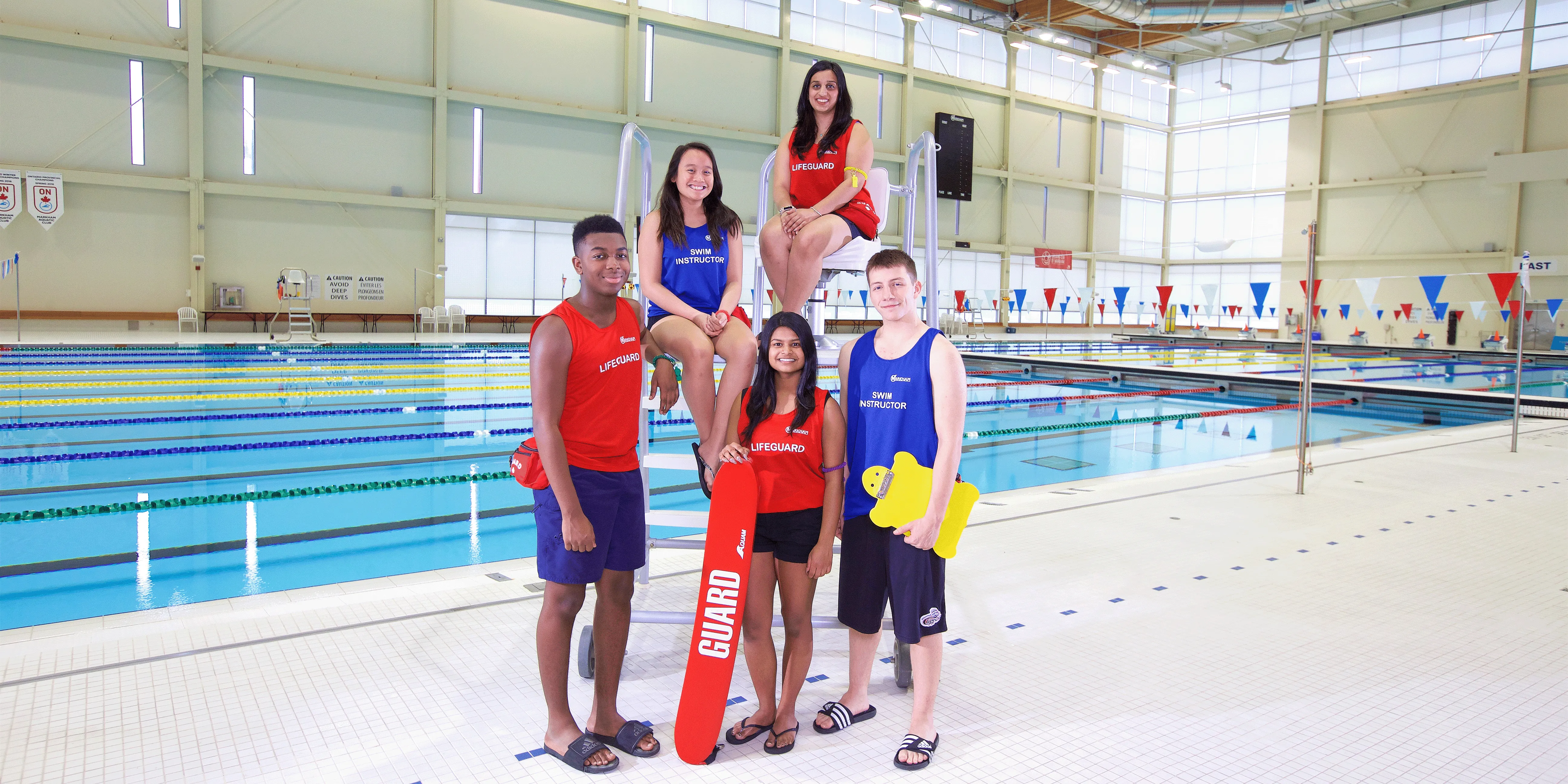 Lifeguards smiling at an indoor pool.