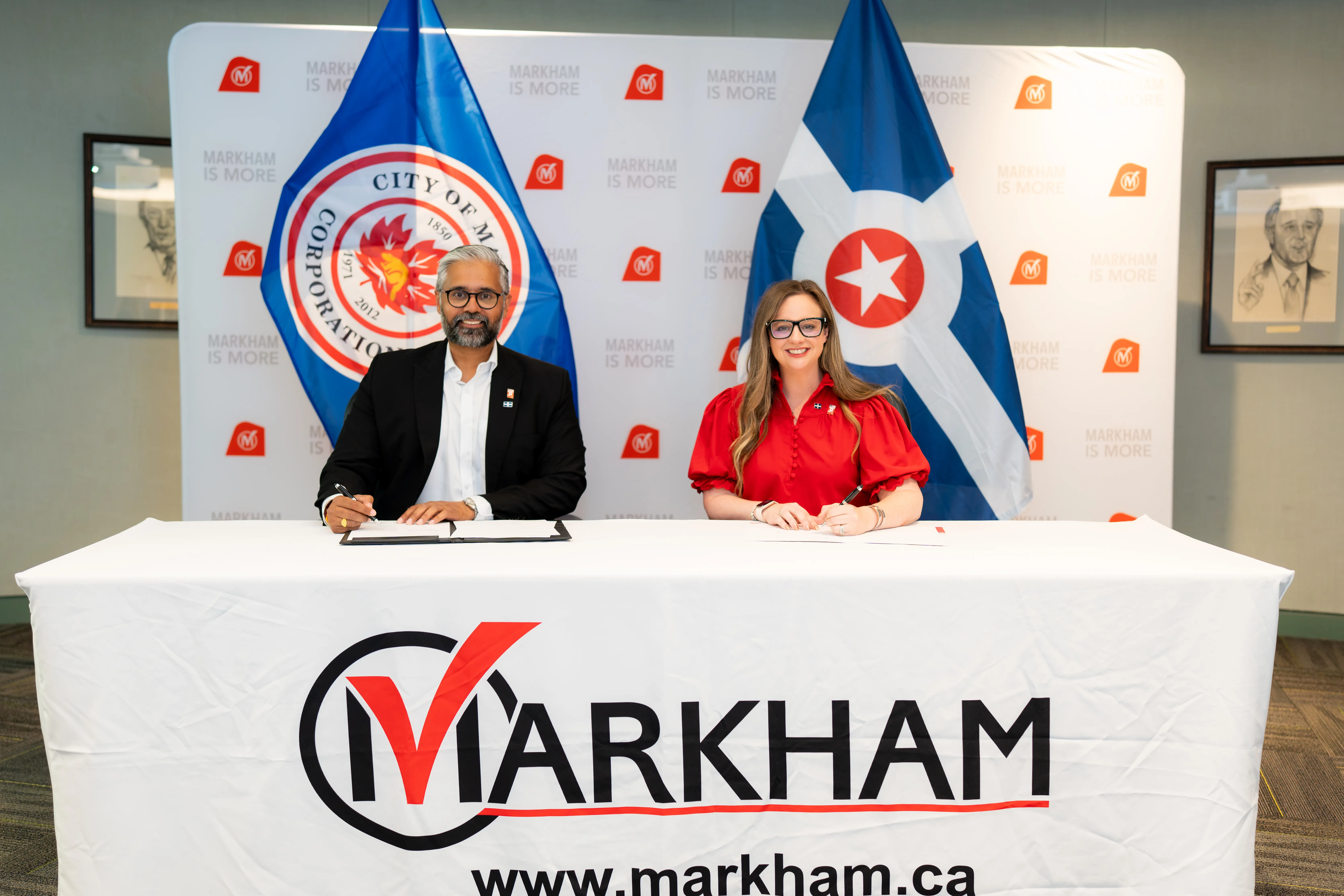 Officials sitting at a table, signing an agreement